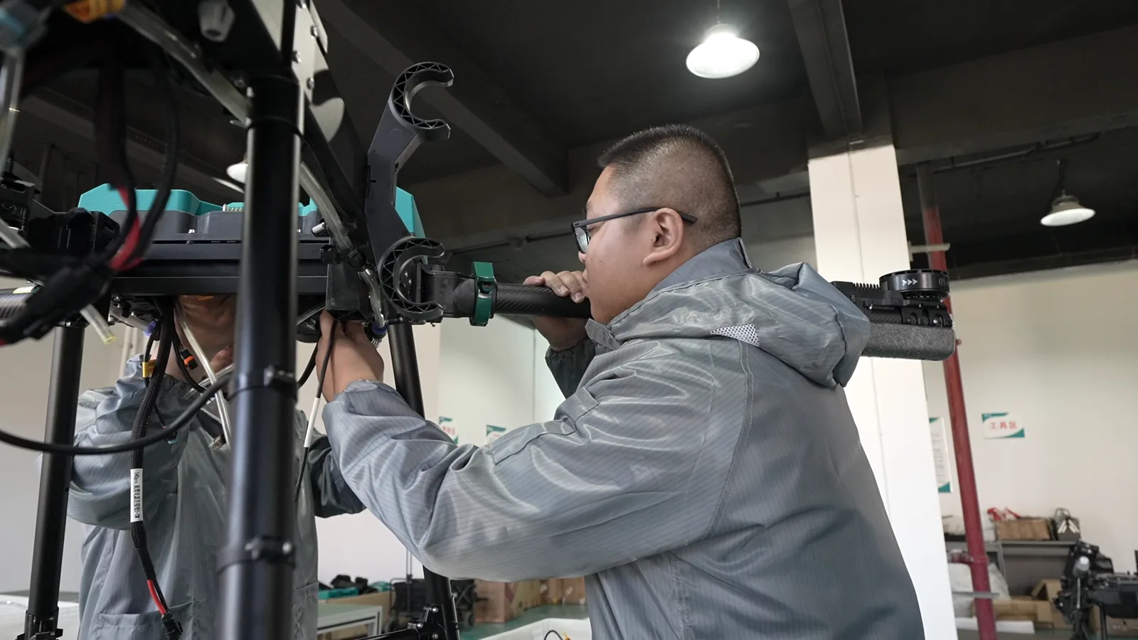 A technician fitting the arm assembly of a JT-80 spray drone at an assembly station