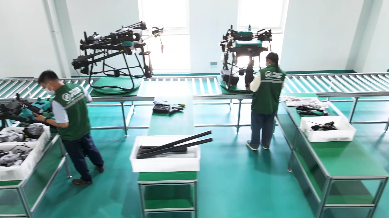 Two technicians checking a spray drone at an inspection station before packing