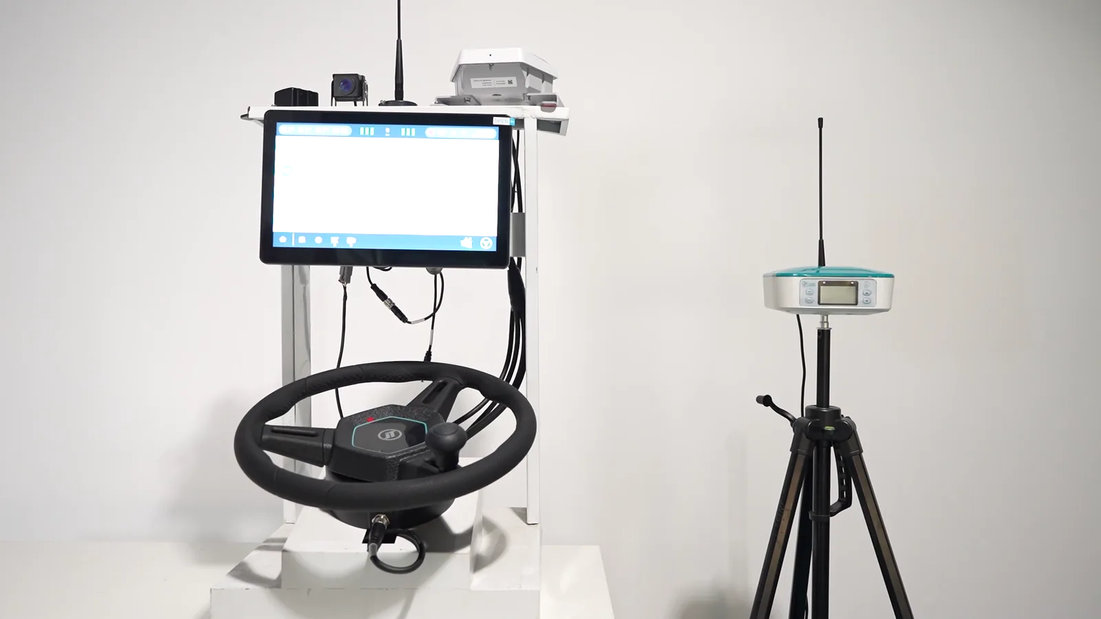 HD818 retrofit kit on a test stand: steering wheel, in-cab display and the GNSS antenna that feeds it
