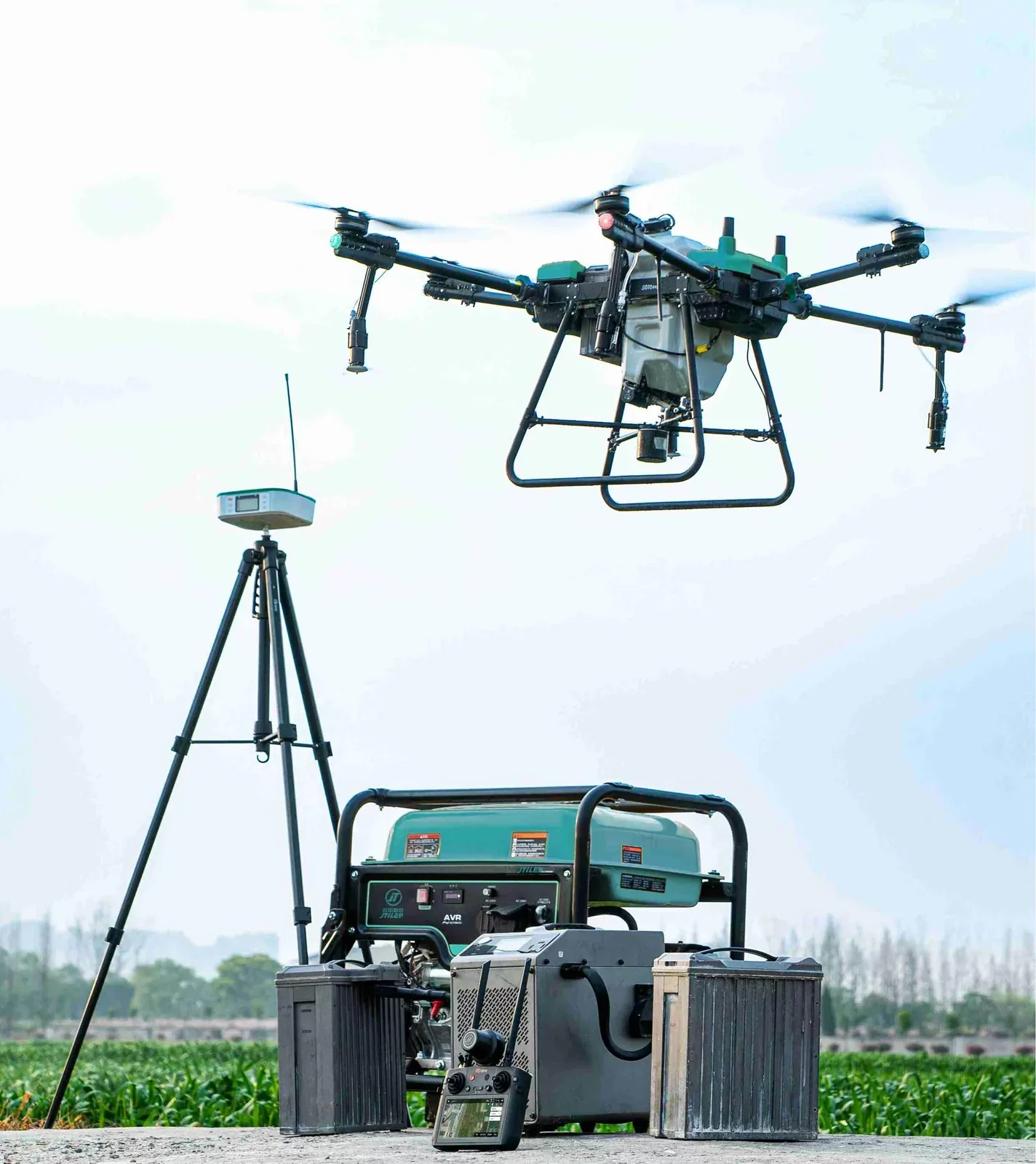 JT-80 hovering beside its full ground station: RTK base station on a tripod, generator, spare battery packs and remote controller