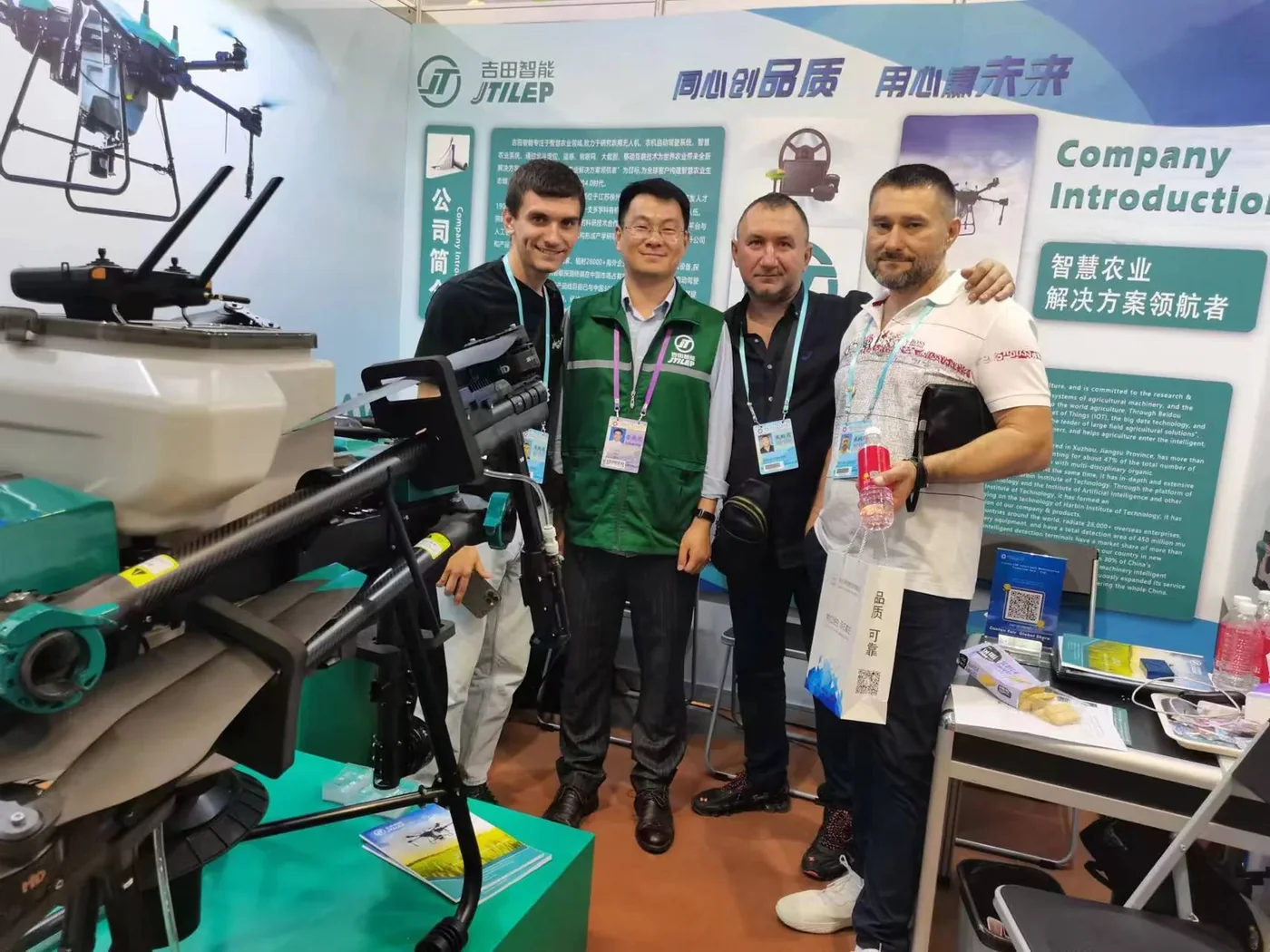 JTILEP and the overseas distributor team photographed with customers at an agricultural machinery exhibition