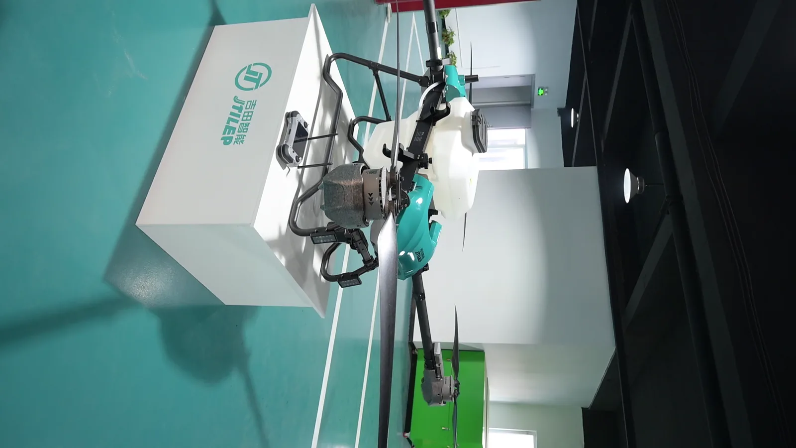 JT-80 agricultural spray drone with tank and arm booms in view, standing on the display plinth